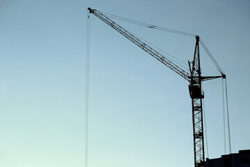 silhouette of a construction crane against the blue sky, panoramic view