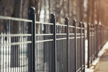 Metal fence in perspective in the park in the spring in the solar reflex