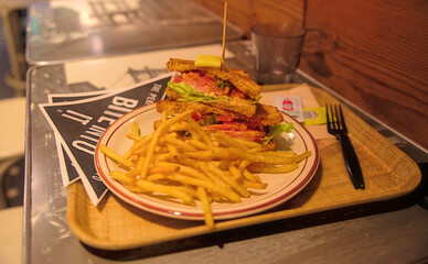 A gourmet toasted BLT sandwich with shoestring french fries on a table in a restaurant