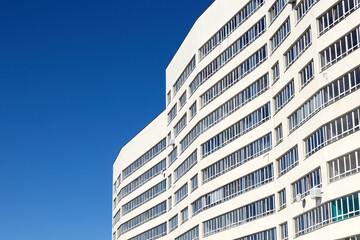 Fototapeta premium A fragment of modern architecture, walls and glass. Windows and balconies of a residential building against a blue sky