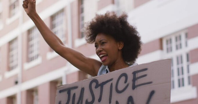 African american woman holding placard shouting raising fist during protest