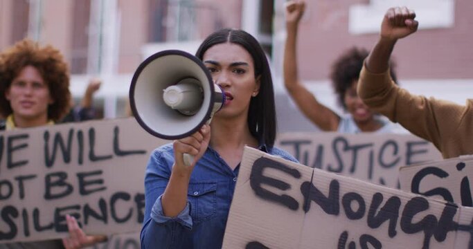 Diverse group of men and women holding placards shouting using megaphone during protest