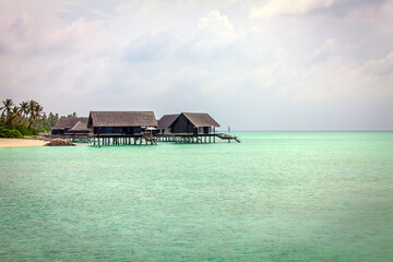 Maldivian Water Bungalows set in the sea green waters of the lagoon.