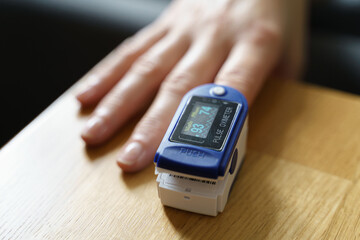 Middle age woman at home checking blood oxygen level with pulse oximeter. Coronavirus covid symptoms. Asthma, lungs decease.