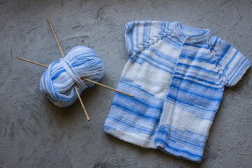 Blue white baby knitted handmade wear with tangle of yarn and needles
