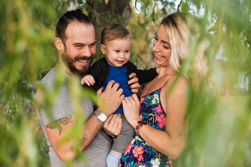 Happy young family spending time together with their sun outside in the park at the sunset. 