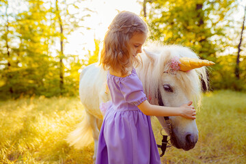 Girl in purple dress hugging white unicorn horse. Dreams come tr