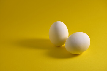 Chicken eggs and eggshells on a yellow background.