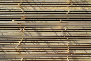 Wooden boards are stacked in rows.
