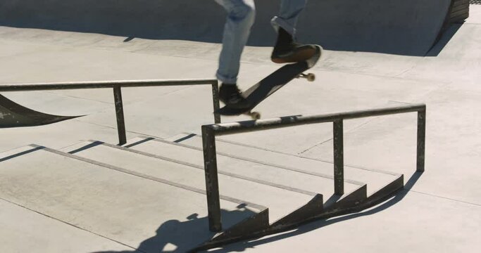 Low section of caucasian man riding and jumping on skateboard on sunny day