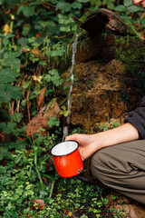 unrecognizable person collecting water from a fountain in the forest. pure water. mountain activities. hiker hydrating.