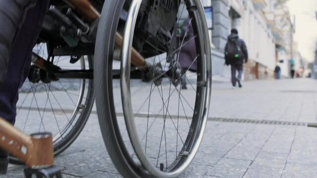 A person with a disability moves along the street in a wheelchair