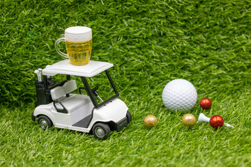 Golf cart and glass of beer are on green grass
