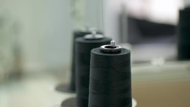 Industrial professional sewing machine, overlock. Coils with fine threads in the workshop. Textile factory, clothing factory. Clothing Manufacturing Industry
