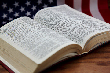 Open Bible with American flag behind reflects concepts of service, dedication, and faithfulness;