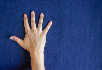 Close-up of open hand with big nails on blue background