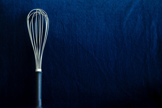 Wire whisk  on blue background in low key
