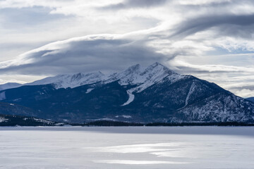Fototapeta na wymiar Clouds over mountain peaks at frozen LakeDillon Colorado on partly cloudy but nice winter day