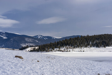 Fototapeta na wymiar View of ski slopes on mountains behind frozen LakeDillon Colorado on partly cloudy winter day