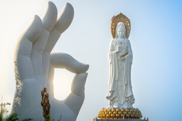 Landscape view of white hand statue with Dharma wheel and Guanyin of the South Sea statue in the...