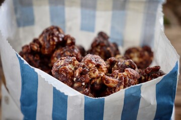 Chocolate covered popcorn and paper bag on wood table
