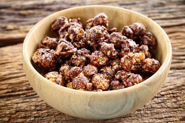 Chocolate covered popcorn on wood bowl on brown table