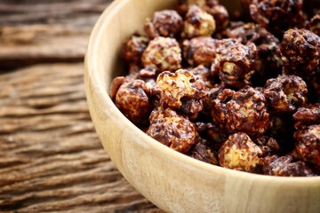 Chocolate covered popcorn on wood bowl on brown table