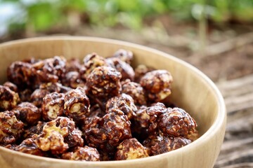 Chocolate covered popcorn on wood bowl on brown table