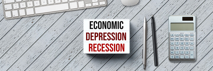lightbox with the message ECONOMIC DEPRESSION - RECESSION and office equipment on wooden background