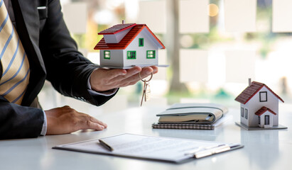 Close up wooden toy house with business woman signs a purchase contract or mortgage for a home, Real estate concept.