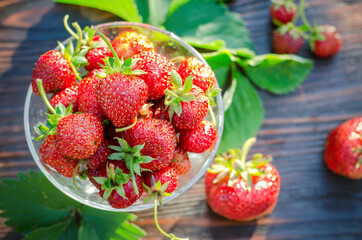 Ripe, organic strawberries in a glass vase on a wooden table