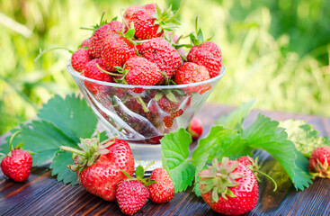Ripe, organic strawberries in a glass vase on a wooden table