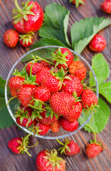 Ripe, organic strawberries in a glass vase on a wooden table