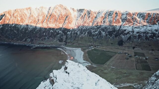 Beautiful sunrise shot from the very edge of a snow-covered mountain, looking over ocean and mountain terrain, Hoddevik, Norway.