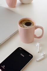 The future is calling, smartphone, bluetooth headphones, coffee and notebook on a white table, in homeoffice