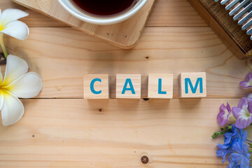 Positive Words Vocabulary  concept, CALM word cube wooden with Coffee mugs, Kalimba and small flowers on the wooden background, start your work day refreshed.