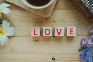 Positive Words Vocabulary  concept, LOVE word cube wooden with Coffee mugs, Kalimba and small flowers on the wooden background, start your work day refreshed.
