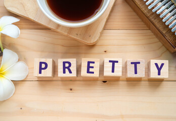 Positive Words Vocabulary  concept, PRETTY word cube wooden with Coffee mugs, Kalimba and small flowers on the wooden background, start your work day refreshed.