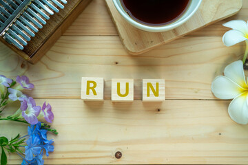 Positive Words Vocabulary  concept, RUN word cube wooden with Coffee mugs, Kalimba and small flowers on the wooden background, start your work day refreshed.