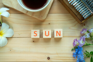 Positive Words Vocabulary  concept, SUN word cube wooden with Coffee mugs, Kalimba and small flowers on the wooden background, start your work day refreshed.