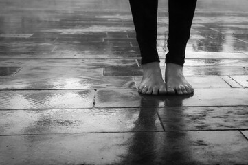 Closeup to woman's feet without shoes on the street and in the rain