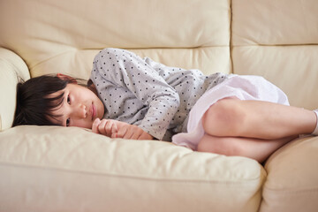 夏のリビングのソファーで休憩している小学生の子供の様子