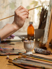 The artist is working on a Still Life. Brush strokes on the canvas. Studio with a desktop easel and...