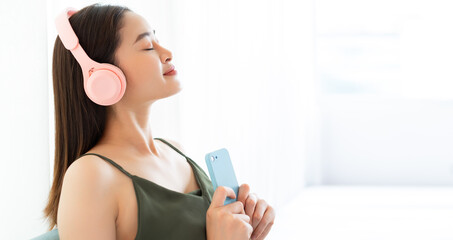 Young Asian woman is closing her eyes and enjoying the music