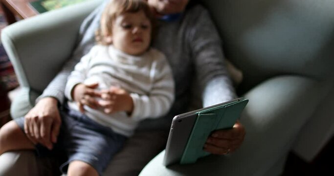 Grandson on grandmother lap watching media on tablet together