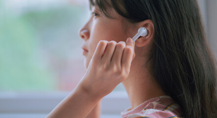 Young Asian woman using wireless earphones to listen music