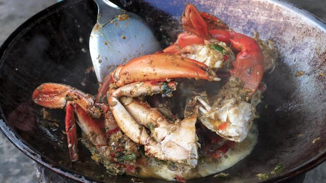 Hot and steaming crab meat cooking in wok style pan, close up view
