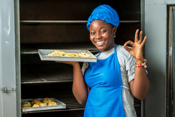 close up image of beautiful african lady in front of a local oven- cheerful black woman in apron...