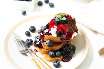 French toast with blueberry jam and berries in a ceramic plate on a white table