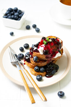 French toast with blueberry jam and berries in a ceramic plate on a white table
